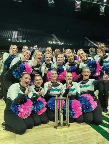 Heritage Pom team holding trophies and colorful pompons.