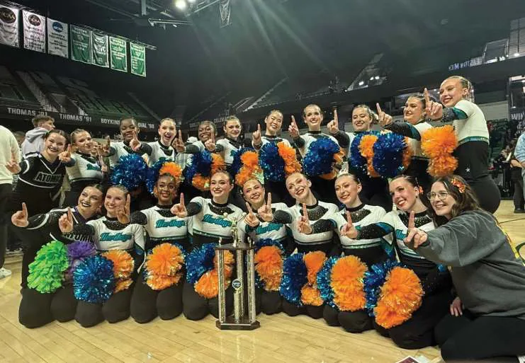The Heritage Pom championship team posing together in an arena.